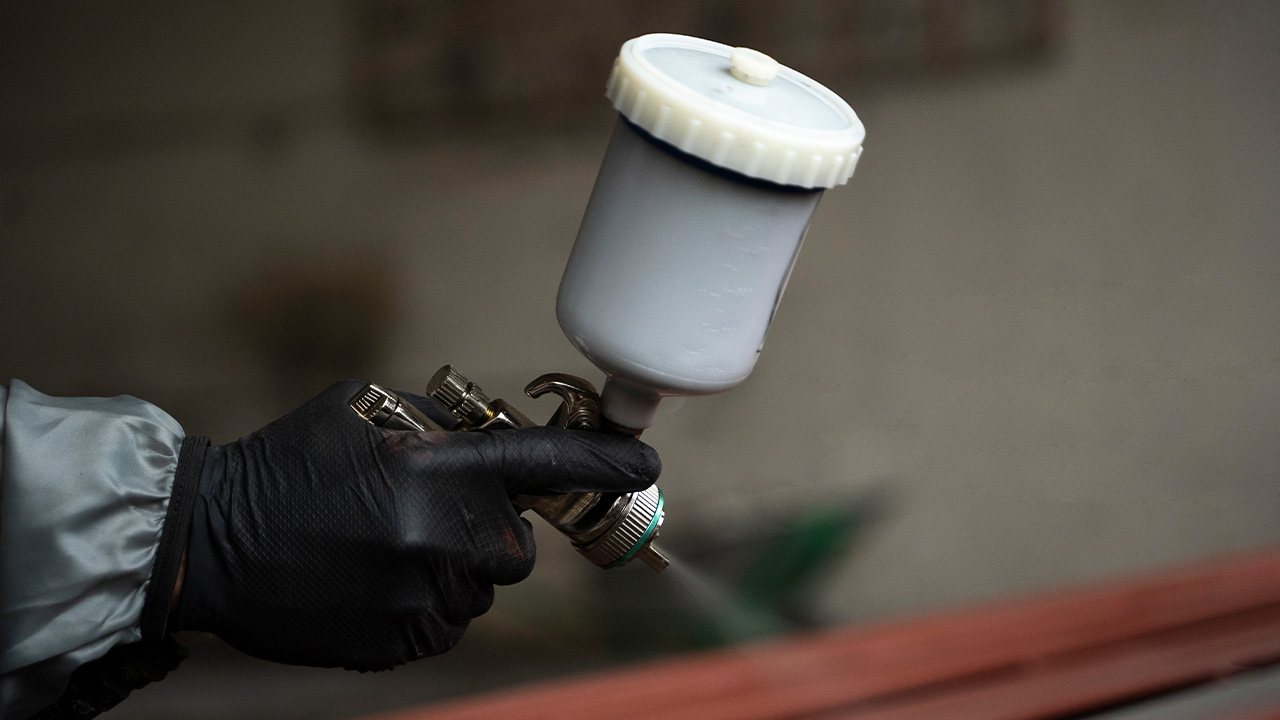Pistola de pintura aplicando tinta, momento onde os defeitos de ambiente aparecem